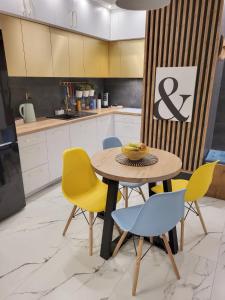 a kitchen with a table and yellow chairs at Apartament Rainbow in Białystok