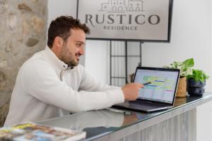 un homme assis à un comptoir avec un ordinateur portable dans l'établissement Residence Rustico, à Garde