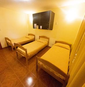 une salle d'hôpital avec trois lits et une armoire dans l'établissement Matices Hostel Terminal, à El Calafate