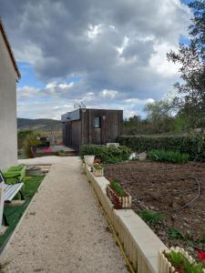 een tuin met een klein gebouw op de achtergrond bij Loft "Plus belle la vue" in Vinezac