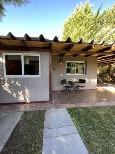 a house with a patio with two chairs and a table at Cabaña Chacras de Caro in Chacras de Coria