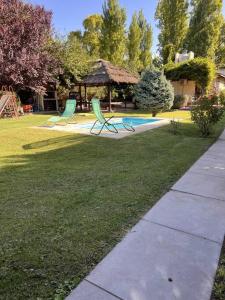 two green chairs in a yard with a gazebo at Cabaña Chacras de Caro in Chacras de Coria