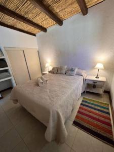 1 dormitorio con 1 cama con 2 lámparas y 1 alfombra en Cabaña Chacras de Caro en Chacras de Coria