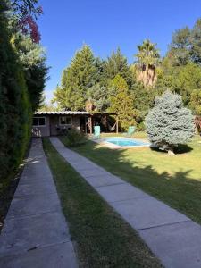 a sidewalk leading to a house with a swimming pool at Cabaña Chacras de Caro in Chacras de Coria