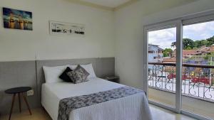een slaapkamer met een bed en een groot raam bij Residencial Dona Virgínia Centro in Canela