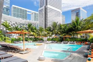 una piscina con sillas, sombrillas y edificios en EAST Miami Residences en Miami