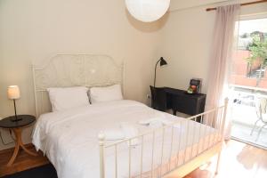 ein Schlafzimmer mit einem weißen Bett und einem Fenster in der Unterkunft Sunny and Quiet 1 Bedroom Apt in Athen