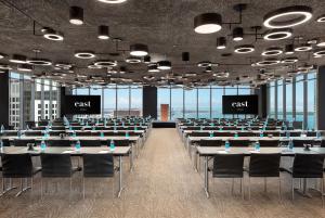 une salle de conférence avec des tables, des chaises et deux écrans dans l'établissement EAST Miami Residences, à Miami