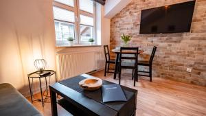 a living room with a table and a tv on a brick wall at Centrum Cicha, Sun & Snow in Krynica Zdrój