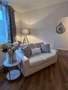 a living room with a couch and a table with flowers at Edge of Glastonbury and Street Town Centre, Ground Floor Large 3 BD With Parking in Street