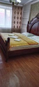 un grande letto in una camera da letto con pavimento in legno di Уютная 3-х комнатная квартира в Хромтау a Khromtaū