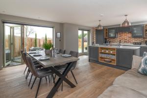 a kitchen and dining room with a table and chairs at Designer Cotswold post house with external sauna in Tetbury