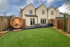 a house with a large lawn in the backyard at Designer Cotswold post house with external sauna in Tetbury