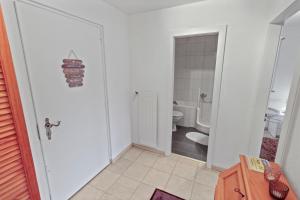bagno bianco con servizi igienici e porta di Joli appartement en plein centre a Nendaz Altre 31 foto