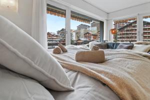 1 cama blanca grande en una habitación con ventanas en Joli appartement en plein centre en Nendaz