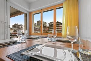 a table with wine glasses and a view of a city at Joli appartement en plein centre in Nendaz