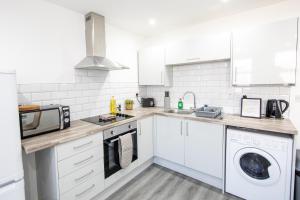 cocina blanca con microondas y lavavajillas en Cosy 1 bed in Stockport centre, en Stockport