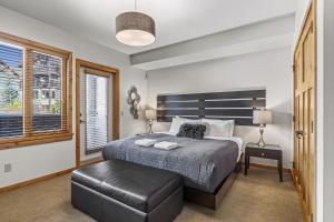 a bedroom with a large bed with a black ottoman at Spring Creek Condo by Canadian Rockies Vacation Rentals in Canmore