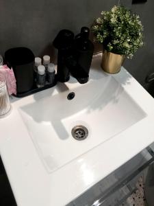 a white sink with a vase of flowers on it at Hola Apartamenty Legionow 2 in Łódź