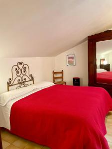 1 dormitorio con cama roja y espejo en La casa di nonna Libia, en Montemerano