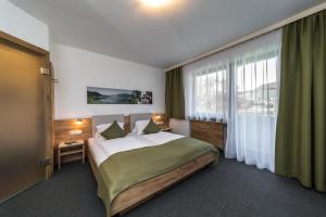 a bedroom with a large bed and a large window at Ticklhof am See in Thiersee