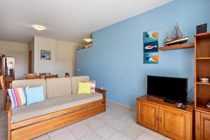 a living room with a couch and a tv at Sonho Dourado Apartamento de praia in Porto Santo