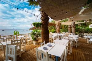 un ristorante con tavoli e sedie bianchi sulla spiaggia di Kampaoh Tossa de Mar a Tossa de Mar