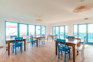 a dining room with tables and chairs and windows at Vila Mavis-cazare cu piscina incalzita 1 mai-30 sept in Mahmudia