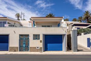 a white house with blue garage doors on a street at Formosa Beach in Porto Santo
