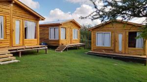 un grupo de cabañas de madera en la hierba en Complejo majua en Cosquín