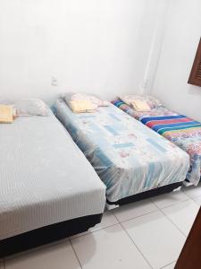 three beds are lined up in a room at Cantinho arretado da Peste - Casa in Aquiraz