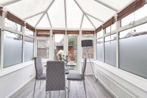 a conservatory with a table and chairs and windows at Luxury 2 Bedroom House with Garden & Free Parking in West Thurrock