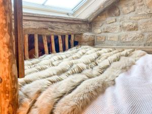 a large white bed with a faux fur blanket at Woolcombers in Addingham