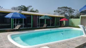 a swimming pool with two umbrellas and a house at Velaria in Chachalacas