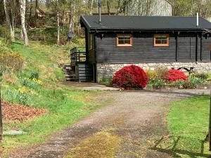 uma cabana preta com uma estrada de cascalho em frente em Squirrel View em Newtonmore