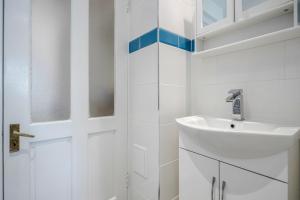 La salle de bains blanche est pourvue d'un lavabo et d'une porte. dans l'établissement Dwellers Delight Living 3 Bed House 2 Bathroom with Wifi & Parking in Prime Location of London Chingford Enfield Area, à Chingford