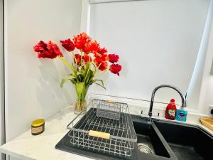 um vaso de flores vermelhas sentado num lavatório da cozinha em Hemel Apartments- Sunset retreat em Hemel Hempstead