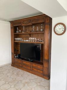 a entertainment center with a television and a clock at Chez Bernard pavillon proche Disneyland et Paris in Coulommiers