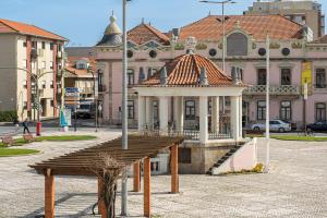 a wooden bench in front of a building at Coreto Garden in Vila do Conde