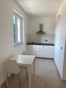 a white kitchen with a white table and chairs at RTA La Pineta in Sarzana