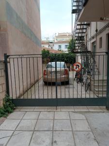 uma cerca com um carro estacionado ao lado de um edifício em Κεντρικό ευρύχωρο στούντιο με parking em Lárissa
