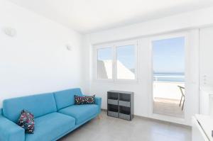 a living room with a blue couch and a window at YourHouse Monges sea view Studio in Can Picafort