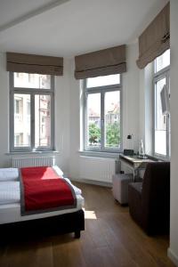 a bedroom with a red bed and a desk and windows at Gideon Hotel in Nürnberg