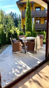 a patio with a table and chairs in front of a house at Dolina Wikingów-apartament Suite z tarasem w ogrodzie, miejscem w garażu i dostępem do strefy wellness in Szklarska Poręba