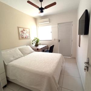 Schlafzimmer mit einem Bett, einem Schreibtisch und einem TV in der Unterkunft Temporada Cuiabana in Cuiabá