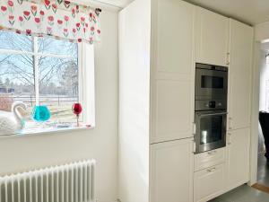uma cozinha com armários brancos e uma janela em Nice holiday home in Balsta em Bålsta