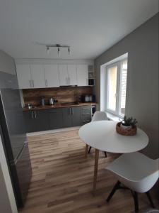 a kitchen with a white table and a white table and chairs at LK Apartment in Rēzekne +15 photos