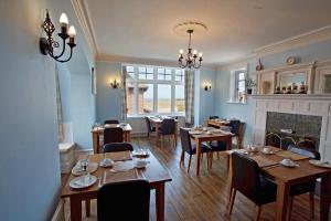 comedor con mesas y sillas y chimenea en Camberley House en Sheringham