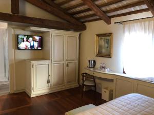 ポンツァーノ・ヴェネトにあるHotel Donna Luciaのベッドルーム1室(壁にテレビとデスク付)
