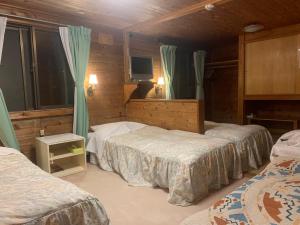 a bedroom with three beds and a tv in it at pension ぽかぽか（poka poka） in Tone